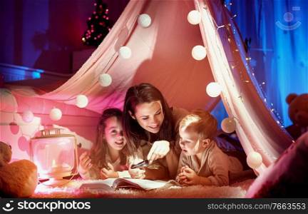 Cheerful, young mother reading a novel for her children