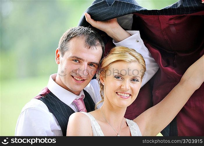 cheerful young pair in wedding day hides from rain