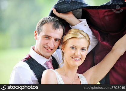 cheerful young pair in wedding day hides from rain