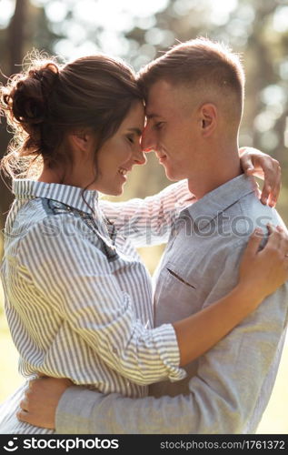 Cheerful young woman and man are hugging outdoors in summer park. Dating and romantic vacation. couple in love gently looking at each other on sunny day. Love and relationships between young people.. Cheerful young woman and man are hugging outdoors in summer park. Dating and romantic vacation. couple in love gently looking at each other on sunny day. Love and relationships between young people