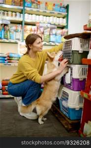 Cheerful young woman customer with dog at pet shop choosing new carrier for transportation during adventure and trip. Cheerful young woman customer with dog at pet shop new choosing carrier
