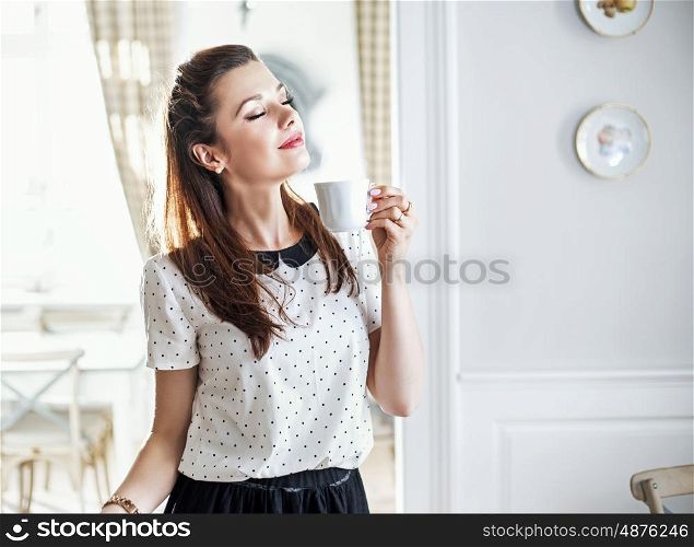 Cheerful young woman drinking morning coffee