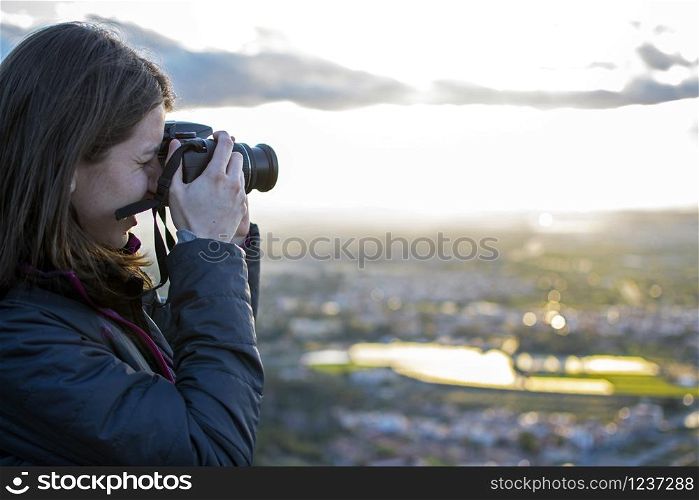 Cheerful young woman hiking and taking pictures with her reflex camera. cheerful young woman hiking and taking pictures with her reflex