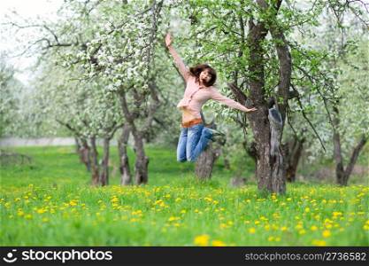 Cheerful young woman jumping in the garden