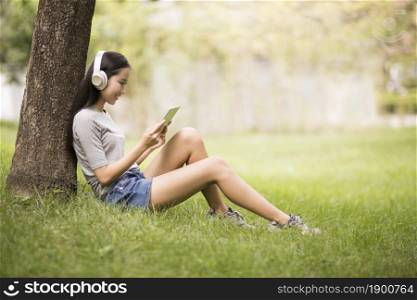 Cheerful young woman listening to music on the lawn