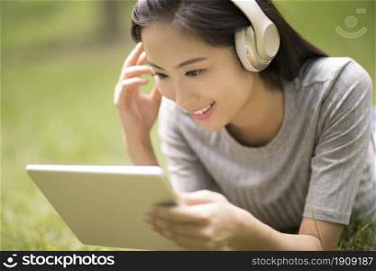 Cheerful young woman listening to music on the lawn