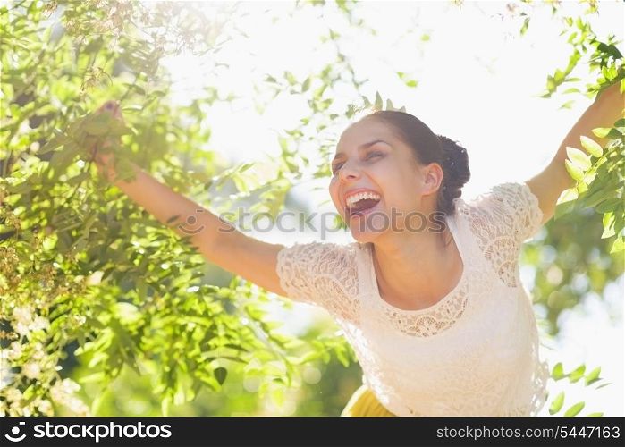 Cheerful young woman playing in foliage in forest