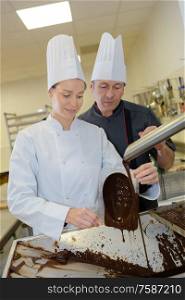 cheerful young woman professional pastry uses chocolate for tasty recipe