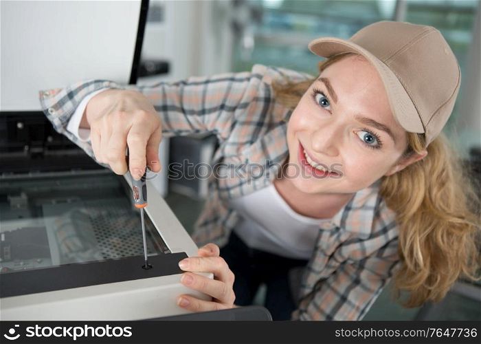 cheerful young woman repairing photocopier