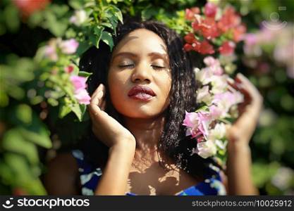Cheerful young woman standing at outdoor with flower.. Portrait of afro American women posing at outdoor.