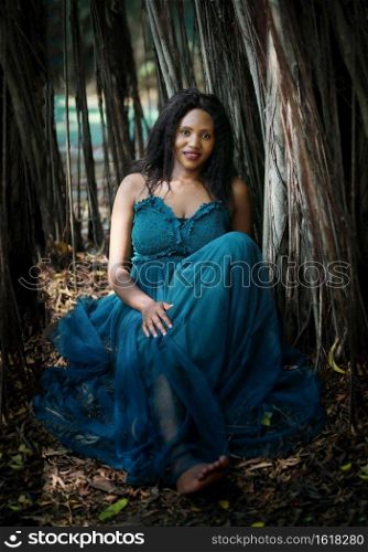 Cheerful young woman standing by tree in the jungle. . Portrait of afro American women posing at outdoor.