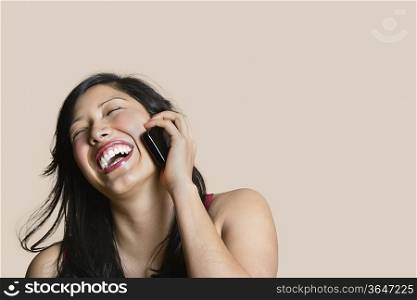 Cheerful young woman talking on mobile phone over colored background