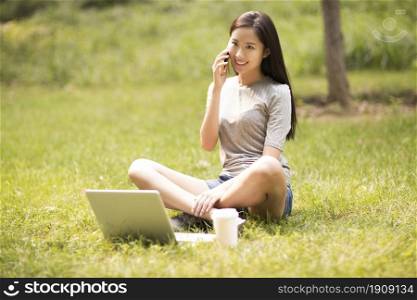 Cheerful young woman talking on the phone on the lawn