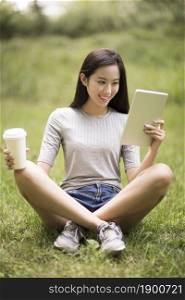 Cheerful young woman using her tablet computer on the lawn