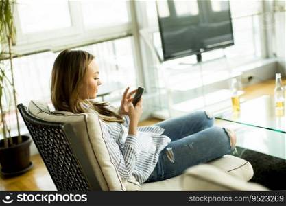 Cheerful young woman watching at cellphone in the room