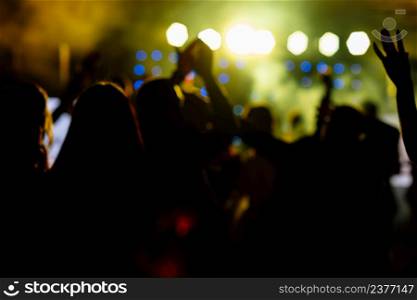 cheering crowd in front of bright yellow stage lights. Silhouette image of people dance in disco night club or concert at a music festival. cheering crowd in front of bright yellow stage lights. Silhouette image of people dance in disco night club or concert at a music festival.