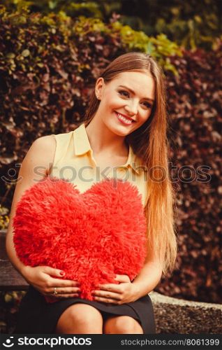 Cheering girl sitting on bench. . Loneliness valentine love romance dating concept. Cheering girl sitting on bench. Young lady holding heart.