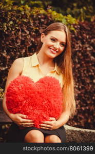 Cheering girl sitting on bench. . Loneliness valentine love romance dating concept. Cheering girl sitting on bench. Young lady holding heart.