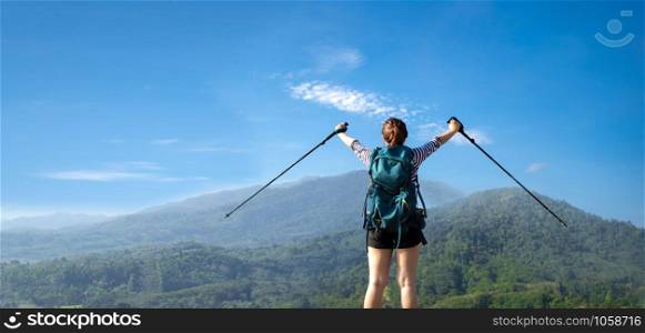 cheering woman hiker open arms at mountain peak.successful woman backpacker hiking on mountain peak
