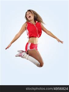 cheerleader girl jumping. Uniformed cheerleader jumps high in the air isolated on white.