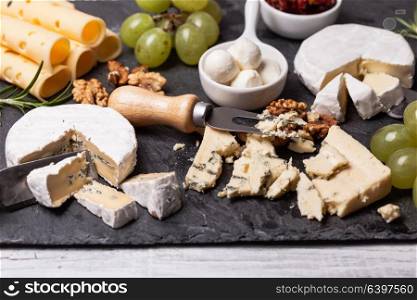 Cheese and grape and nuts on a slate board. Cheese delicious plate