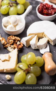 Cheese and grape and nuts on a slate board. Cheese delicious plate