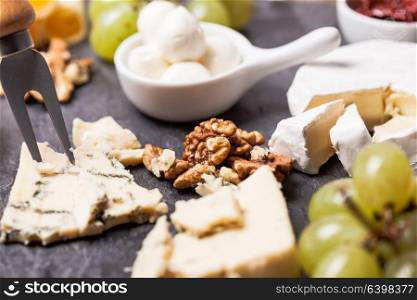 Cheese and grape and nuts on a slate board. Cheese delicious plate