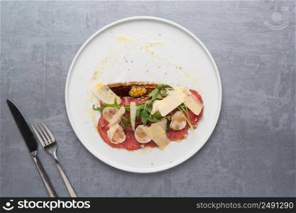 cheese and meat with greens in a plate on a gray background. the food, the view from the top