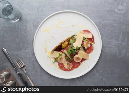 cheese and meat with greens in a plate on a gray background. the food, the view from the top