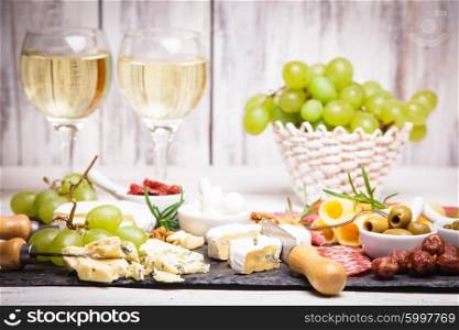 Cheese and salami on a slate board and grape wine. Cheese and salami plate