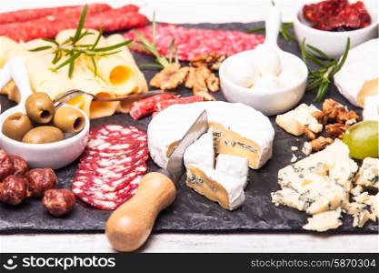 Cheese and salami with olives and nuts on a slate board. Cheese and salami plate