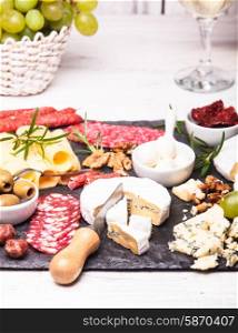 Cheese and salami with olives and nuts on a slate board. Cheese and salami plate