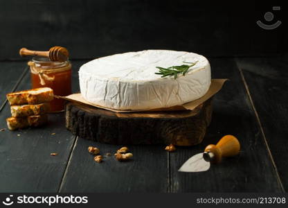 Cheese brie with honey and rosemary on a dark background