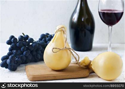 Cheese Caciocavallo a glass and a bottle of red wine, grapes. Cheese pear.. Cheese Caciocavallo a glass and a bottle of red wine, grapes. Cheese pear