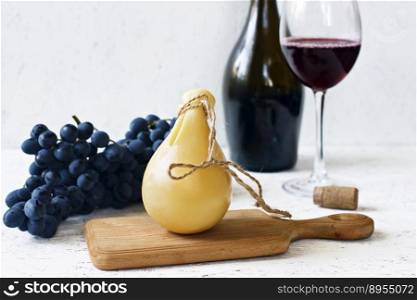 Cheese Caciocavallo a glass and a bottle of red wine, grapes. Cheese pear.. Cheese Caciocavallo a glass and a bottle of red wine, grapes. Cheese pear