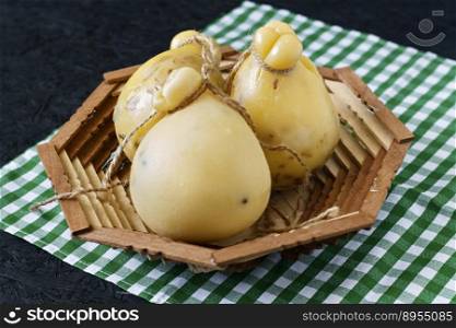 Cheese Caciocavallo in a basket on a black background. Cheese pear.. Cheese Caciocavallo in a basket on a black background. Cheese pear