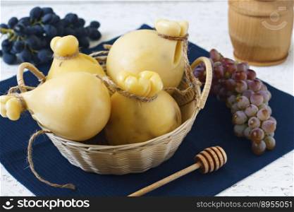 Cheese Caciocavallo in a basket with honey and grapes on a white background. Cheese pear.. Cheese Caciocavallo in a basket with honey and grapes on a white background. Cheese pear