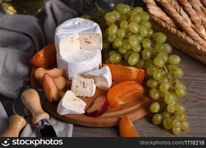 Cheese camembert with white grapes, sliced persimmons and plums, a great appetizer for wine