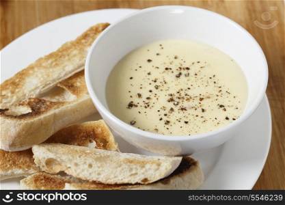 Cheese dip, made with soft cheese, milk, egg and butter in a bain marie, sprinkled with pepper and served with toasted ciabata crostini.