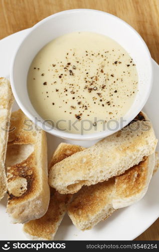 Cheese dip, made with soft cheese, milk, egg and butter in a bain marie, sprinkled with pepper and served with toasted ciabata crostini.