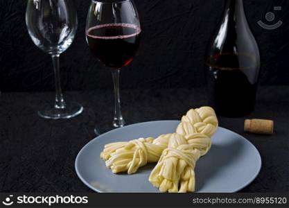 Cheese on a plate and wine on a black background. Sulguni cheese.. Cheese on a plate and wine on a black background. Sulguni cheese