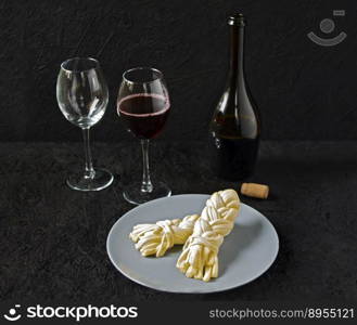 Cheese on a plate and wine on a black background. Sulguni cheese.. Cheese on a plate and wine on a black background. Sulguni cheese