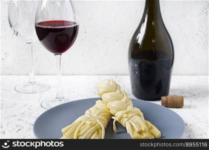 Cheese on a plate and wine on a white background. Sulguni cheese.. Cheese on a plate and wine on a white background. Sulguni cheese