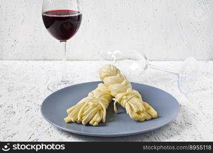 Cheese on a plate and wine on a white background. Sulguni cheese.. Cheese on a plate and wine on a white background. Sulguni cheese