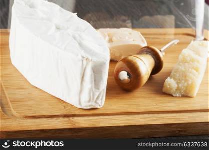 Cheese over wooden chopping board, close up, horizontal image