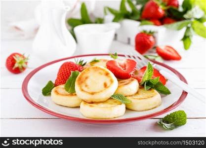 Cheese pancakes, fritters or syrniki with fresh strawberry and yogurt. Healthy and tasty breakfast