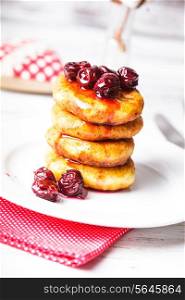 cheese pancakes with cherry jam on the plate