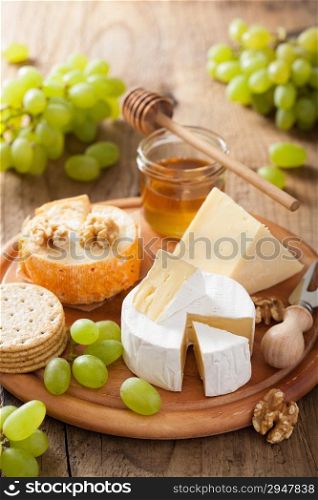 cheese plate with camembert, cheddar, grapes and honey