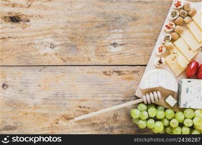 cheese platter served with red tomatoes grapes wooden table