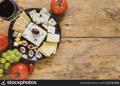 cheese platter with tomatoes grapes wooden desk